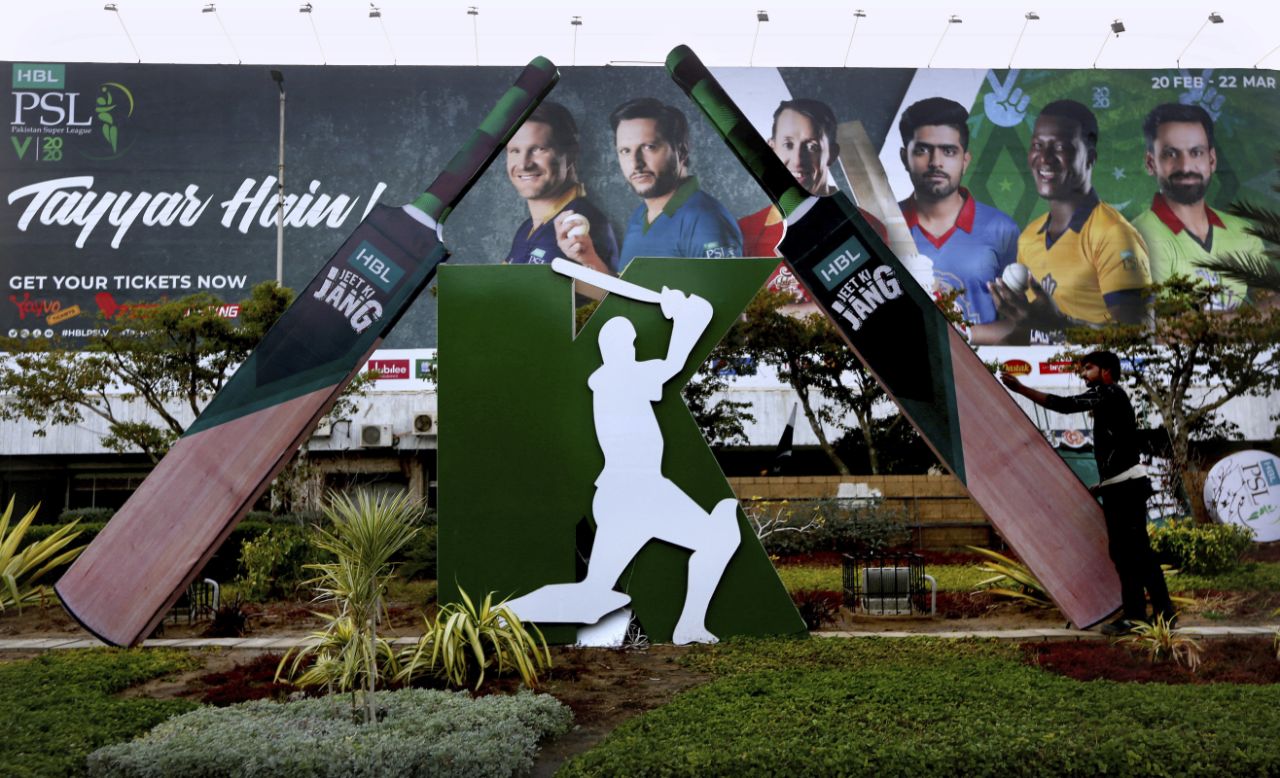 Pakistan Cricket Progress In this Saturday, Feb. 15, 2020 photo, a worker install a cut-out of huge bats next to a poster of cricketers displays along roadside in preparation of the upcoming Pakistan Super League, in Karachi, Pakistan. (AP)