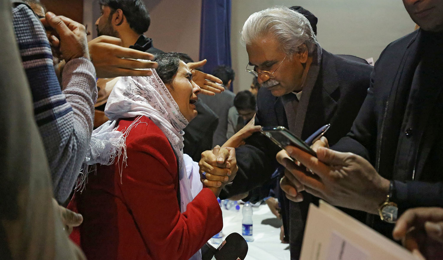 Pakistan's Health Minister, Zafar Mirza (R), interacts with the mother of a Pakistani student, who is stuck in the locked down Hubei province at the center of China's coronavirus outbreak, as people demand evacuation of their children during a meeting in Islamabad on Feb. 19, 2020. (REUTERS)