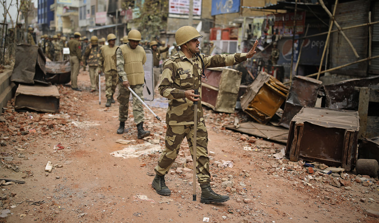 An Indian paramilitary soldier asks residents to stay indoors as they patrol a street vandalized in Tuesday's violence in New Delhi on Feb. 27, 2020. (AP)