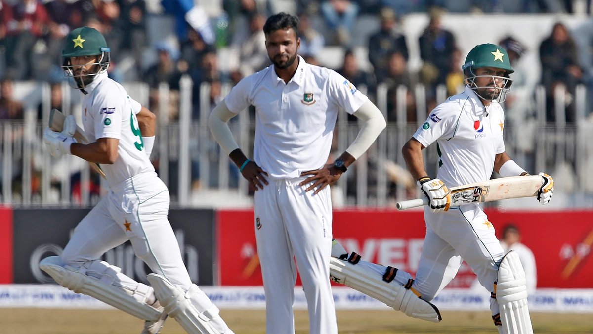 Pakistani batsmen Shan Masood, left, and Babar Azam, right, run between the wickets as Bangladesh pacer Ebadot Hossain looks on during their second day of the first test cricket match at Rawalpindi cricket stadium in Rawalpindi on Feb. 8, 2020. (AP)