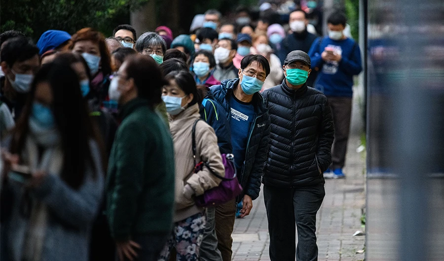 People wearing facemasks as a preventative measure following a coronavirus outbreak which began in the Chinese city of Wuhan, line up to purchase face masks from a makeshift stall on February 5, 2020. (AFP)