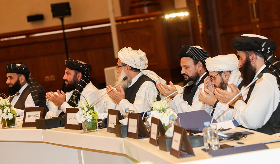 Members of the Taliban attending the second day of the Intra Afghan Dialogue talks raise their hands as they recite a prayer while seated during the talks in the Qatari capital Doha on July 8, 2019. (AFP)