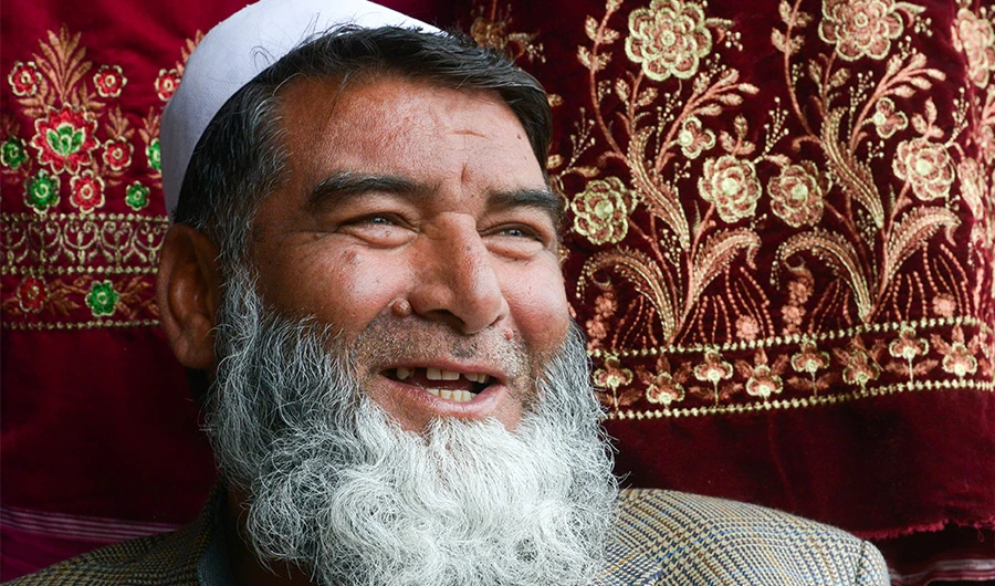 In this picture taken on February 12, 2020, Afghan refugee Mohammad Feroz smiles as he waits for customers at his clothing shop in a bazaar at a neighbourhood locally known as 'mini Kabul' in Peshawar. (AFP)