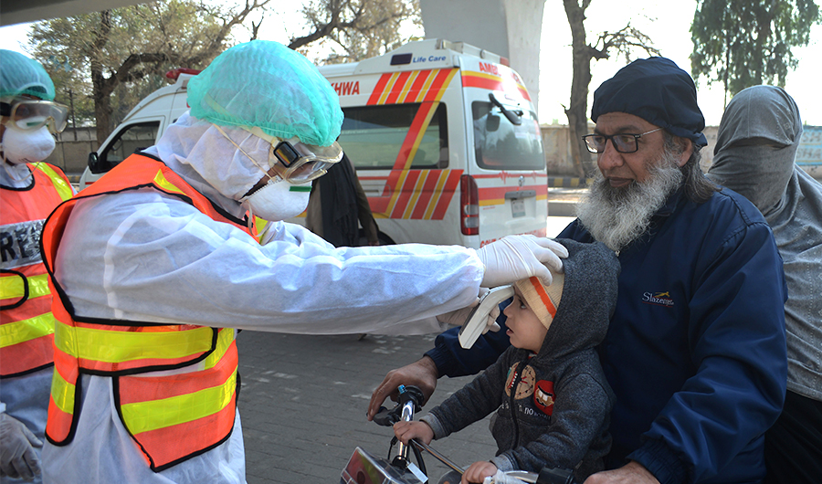A Pakistani rescue personnel checks the body temperature of a boy during a drill exercise as a preventive measure for the spread of the of COVID-19 coronavirus, in Peshawar on March 1, 2020, as Pakistan has detected two new cases of the novel coronavirus. (AFP)