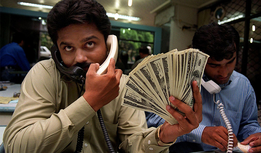 Pakistani money dealers busy on telephones amid a spurt in demand for the green back in the port city of Karachi, 27 May 2000. (AFP)