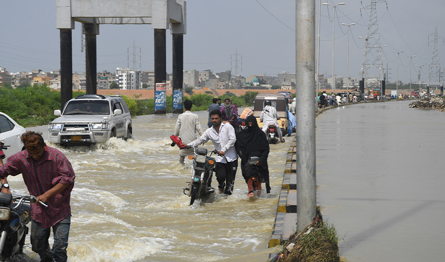 Commuters make their way on a flooded street after heavy monsoon rains in the Pakistan's port city of Karachi on September 3, 2019. (AFP)