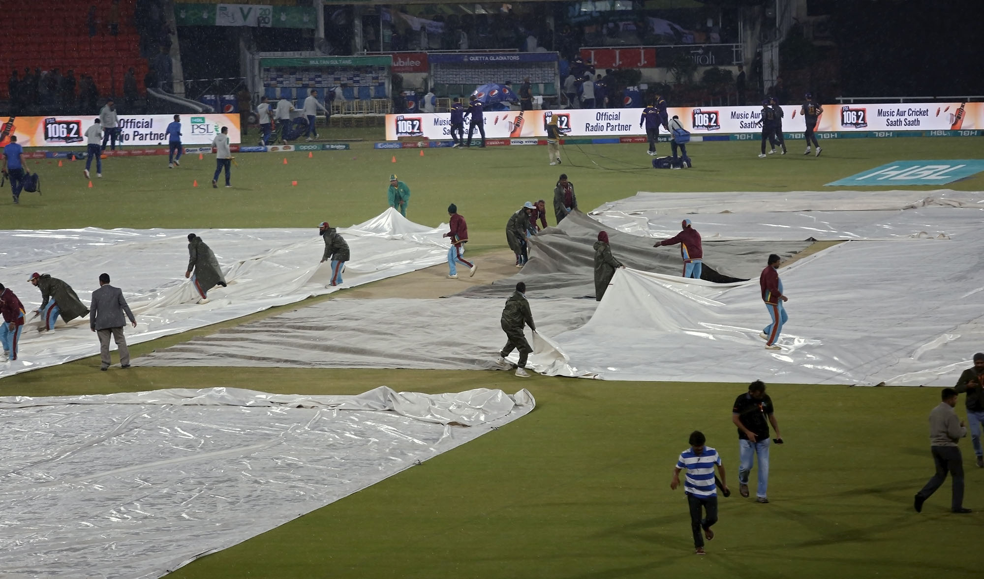 Ground staff at Gadaffi Stadium cover the wicket and the square just before heavy rain abandoned the Pakistan Super League match between title defender Quetta Gladiators and Multan Sultans in Lahore on March 11, 2020. (AP)