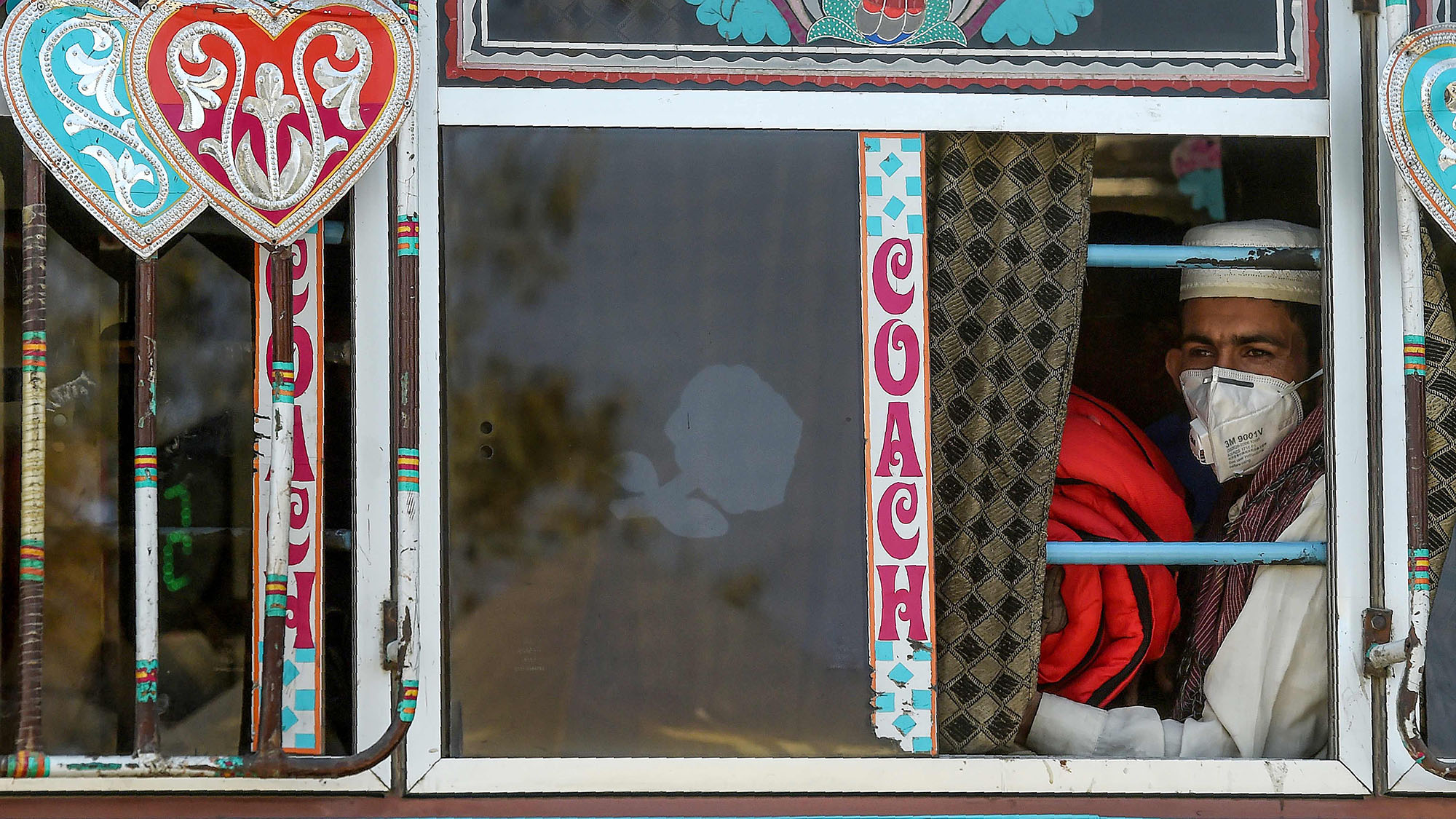 A passenger wearing a facemask as a prevention measure against the coronavirus sits in a bus in Karachi on March 11, 2020. (AFP)