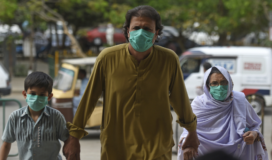 A family wearing facemasks amid concerns over the spread of the COVID-19 novel coronavirus, arrive at the railway station in Karachi on March 15, 2020. (AFP)