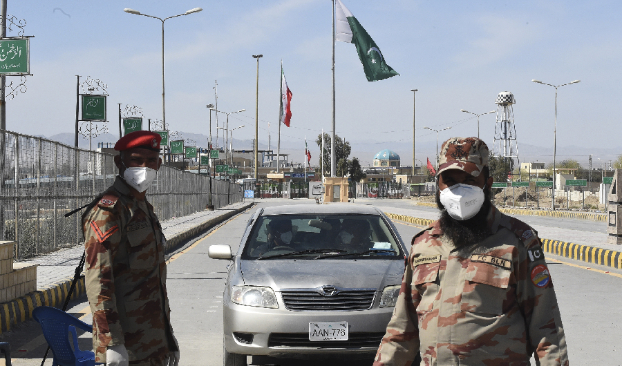 Pakistani soldiers wearing facemasks stand at the closed Pakistan-Iran border in Taftan on February 25, 2020 as fears over the spread of the COVID-19 coronavirus escalate following an outbreak in neighbouring Iran. (AFP)