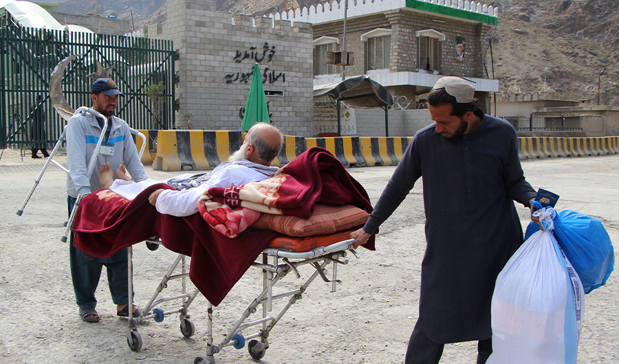 An Afghan national drags a stretcher carrying a patient before crossing the border into Afghanistan from Pakistan at the Torkham Border Post in Pakistan's Khyber Agency on March 7, 2017. (AFP)