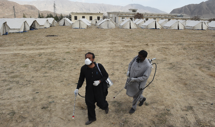 Workers of the Provincial Disaster Management Authority (PDMA) of Balochistan arrive to spray disinfectant at a quarantine camp, prepared for people returning from Iran via the Pakistan-Iran border town of Taftan to prevent the spread the COVID-19 coronavirus, on the outskirts of Quetta on March 9, 2020. (AFP)
