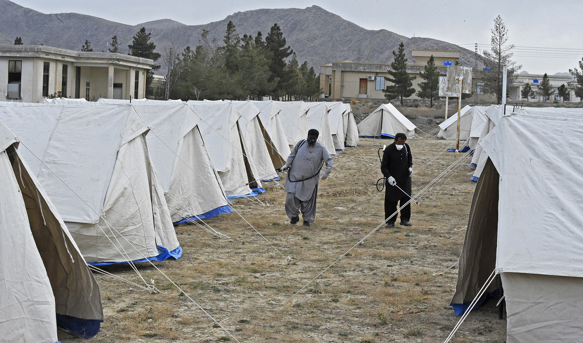 Workers of the Provincial Disaster Management Authority (PDMA) of Balochistan spray disinfectant on tents at a quarantine camp, prepared for people returning from Iran via the Pakistan-Iran border town of Taftan to prevent the spread the coronavirus on March 9, 2020. (AFP)