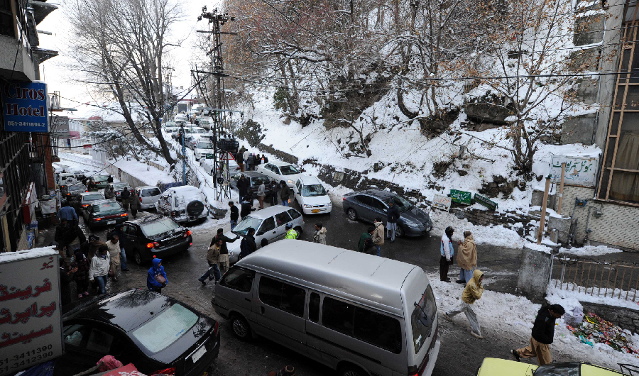 People walk past tourists vehicles stuck in a traffic jam in snow covered area in Murree, some 50kms north of Islamabad on January 7, 2012. (AFP)