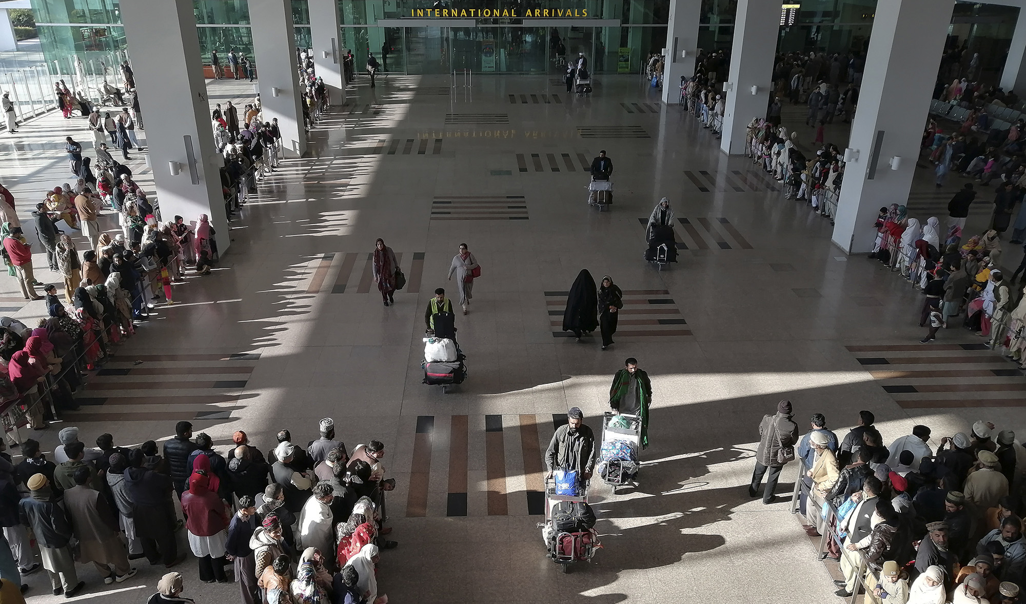 In this file photo, people gather to receive arriving passengers at the international arrival area of the Islamabad International Airport in Islamabad on Feb. 3, 2020. (AFP)