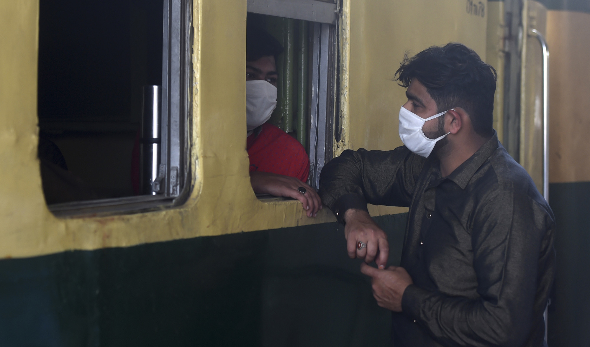 In this file photo, people wear facemasks amid concerns over the spread of the COVID-19 novel coronavirus chat before the departure of a train at Karachi Cantonment railway station in Karachi on March 16, 2020. (AFP)