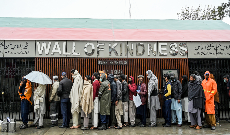 People queue as they wait to receive charity food alongside a road during a government-imposed lockdown as a preventive measure against the COVID-19 coronavirus, in Rawalpindi on March 24, 2020. (AFP)