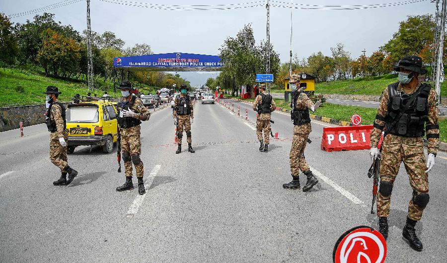 Security personnel wearing facemasks stand guard at a checkpoint at the city's entrance during lockdown as a preventive measure against the COVID-19 coronavirus in Islamabad on March 26, 2020. (AFP)