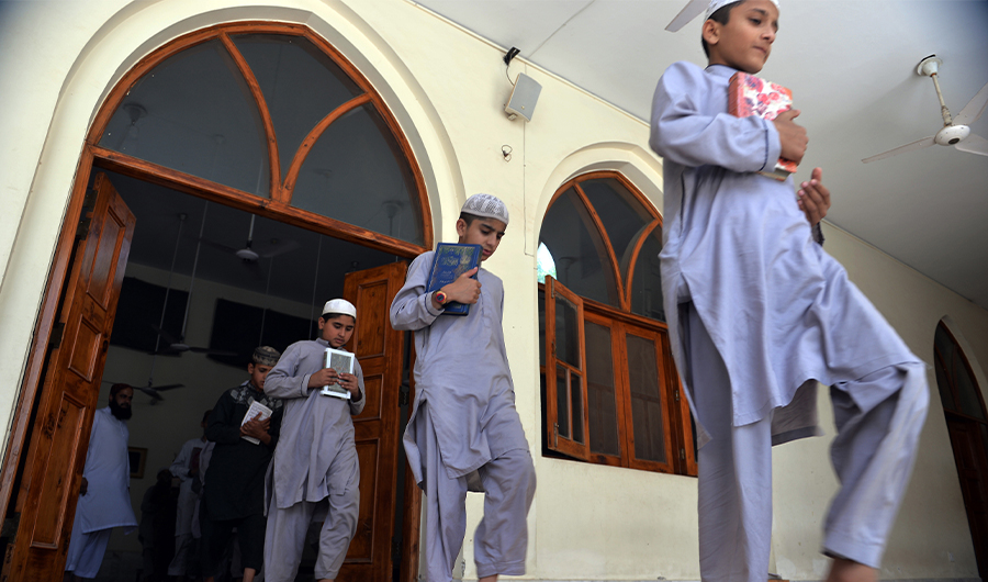 This photograph taken on May 5, 2015 shows Pakistani students of a madrassa or Islamic school carry the Quran as they leave class at their seminary in Islamabad. (AFP)