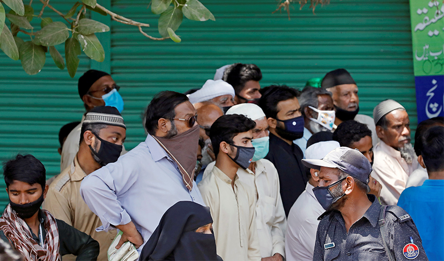 A police officer (R) asks people to disperse as they gather to receive ration handouts at a distribution point of a charity, during a lockdown after Pakistan shut all markets, public places and discouraged large gatherings amid an outbreak of coronavirus disease (COVID-19), in Karachi, Pakistan, March 28, 2020. (REUTERS)