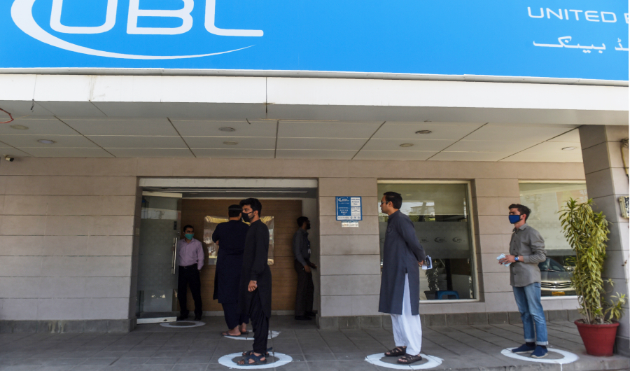Residents stand in designated areas marked on the ground to maintain social distanciation outside a bank during a government-imposed nationwide lockdown as a preventive measure against the COVID-19 coronavirus, in Karachi on March 27, 2020. (AFP)