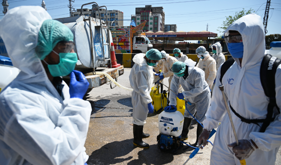 Workers wearing protective gear prepare to spray disinfectant at a residential area during a government-imposed nationwide lockdown as a preventive measure against the COVID-19 coronavirus, in Islamabad on March 29, 2020. (AFP)