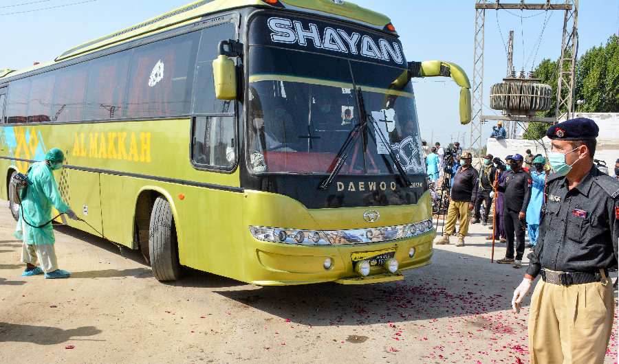 A soldier wearing a facemask stands guard as buses carry pilgrims returning from Iran via the Pakistan-Iran border town of Taftan, leading to a quarantine facility zone to prevent the spread the COVID-19 novel coronavirus, in Sukkur in southern Sindh province on March 18, 2020. (AFP)