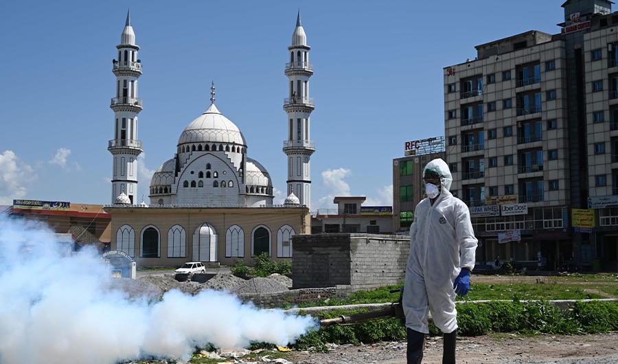 A worker wearing protective gear sprays disinfectant at a street at a residential area during a government-imposed nationwide lockdown as a preventive measure against the COVID-19 coronavirus, in Islamabad on March 29, 2020. (AFP)