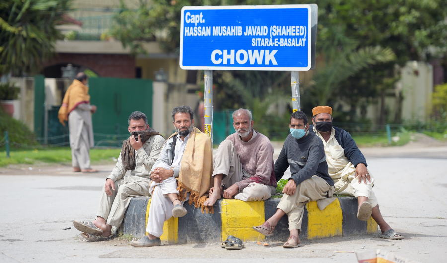 Laborers are sitting on a street in Rawalpindi on March 25, 2020. (AFP)