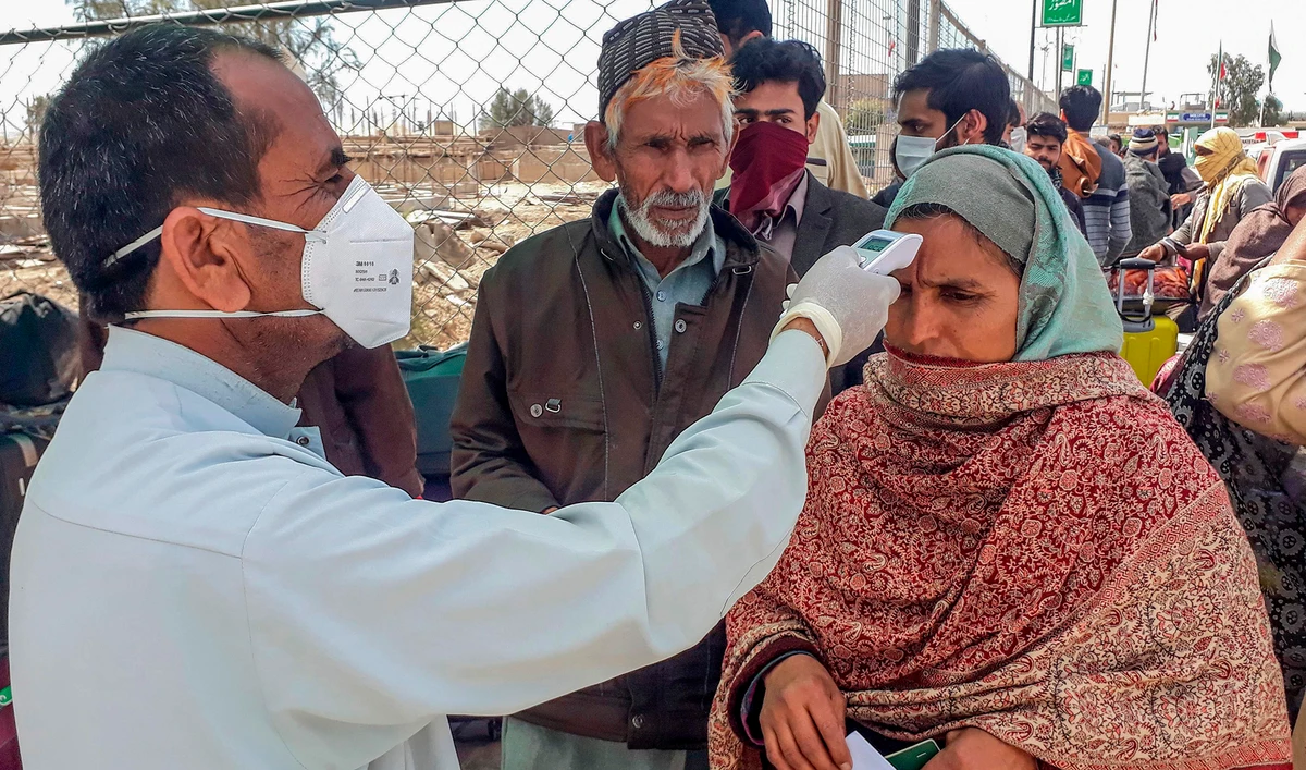 In this file photo, a health personnel checks the body temperature of a pilgrim returning from Iran via the Pakistan-Iran border town of Taftan on Feb. 29, 2020. (REUTERS)