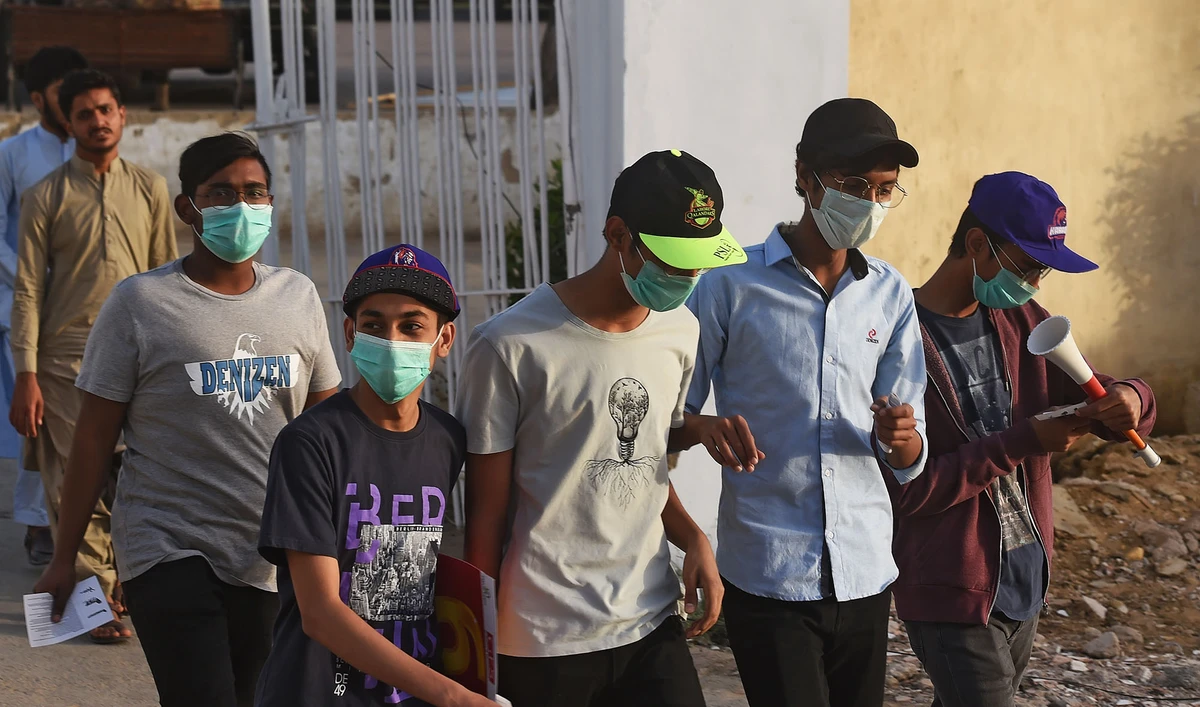 Cricket fans wearing facemasks amid concerns of the spread of the COVID-19 coronavirus, arrive at the National Cricket Stadium in Karachi on March 12, 2020. (AFP)