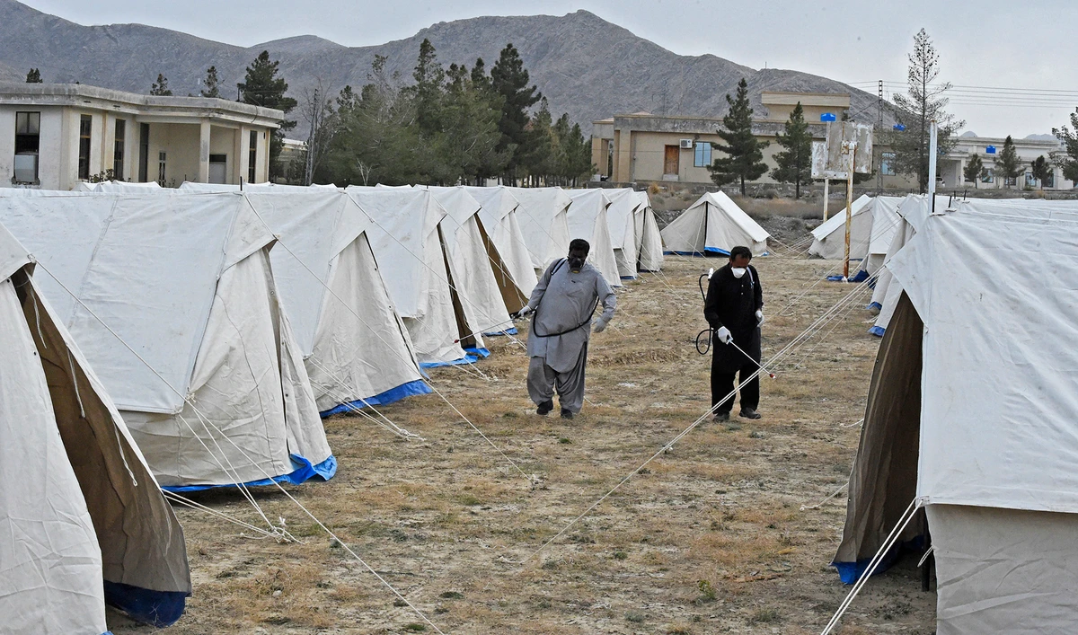 Workers of the Provincial Disaster Management Authority (PDMA) of Balochistan spray disinfectant on tents at a quarantine camp, prepared for people returning from Iran via the Pakistan-Iran border town of Taftan to prevent the spread the coronavirus on March 9, 2020. (AFP)