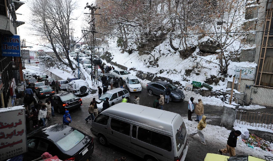 People walk past tourists vehicles stuck in a traffic jam in snow covered area in Murree, some 50kms north of Islamabad on January 7, 2012. (AFP)