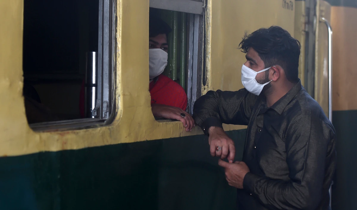 In this file photo, people wear facemasks amid concerns over the spread of the COVID-19 novel coronavirus chat before the departure of a train at Karachi Cantonment railway station in Karachi on March 16, 2020. (AFP)