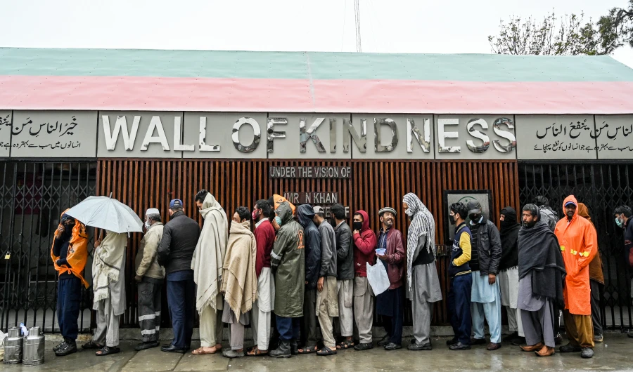 People queue as they wait to receive charity food alongside a road during a government-imposed lockdown as a preventive measure against the COVID-19 coronavirus, in Rawalpindi on March 24, 2020. (AFP)