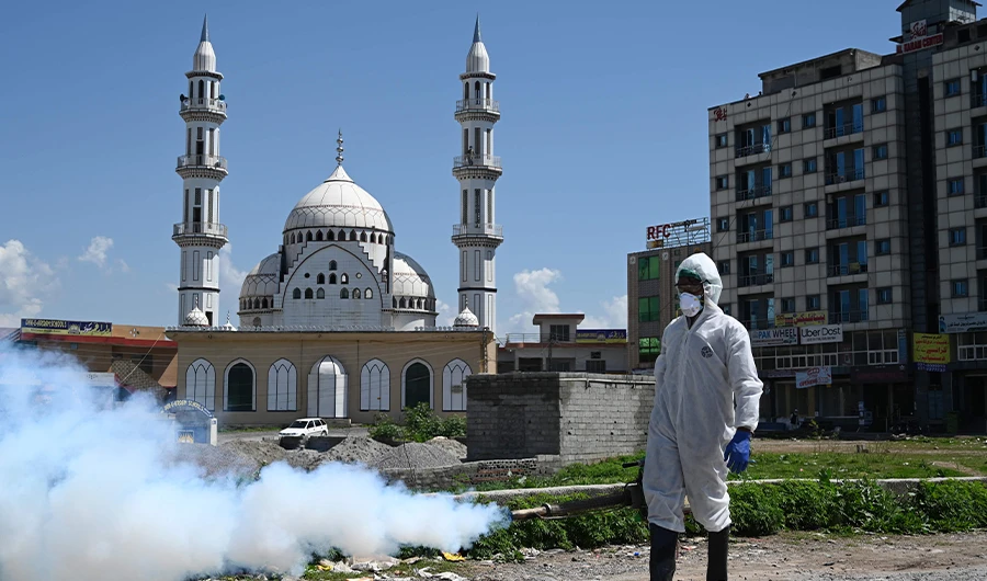 A worker wearing protective gear sprays disinfectant at a street at a residential area during a government-imposed nationwide lockdown as a preventive measure against the COVID-19 coronavirus, in Islamabad on March 29, 2020. (AFP)