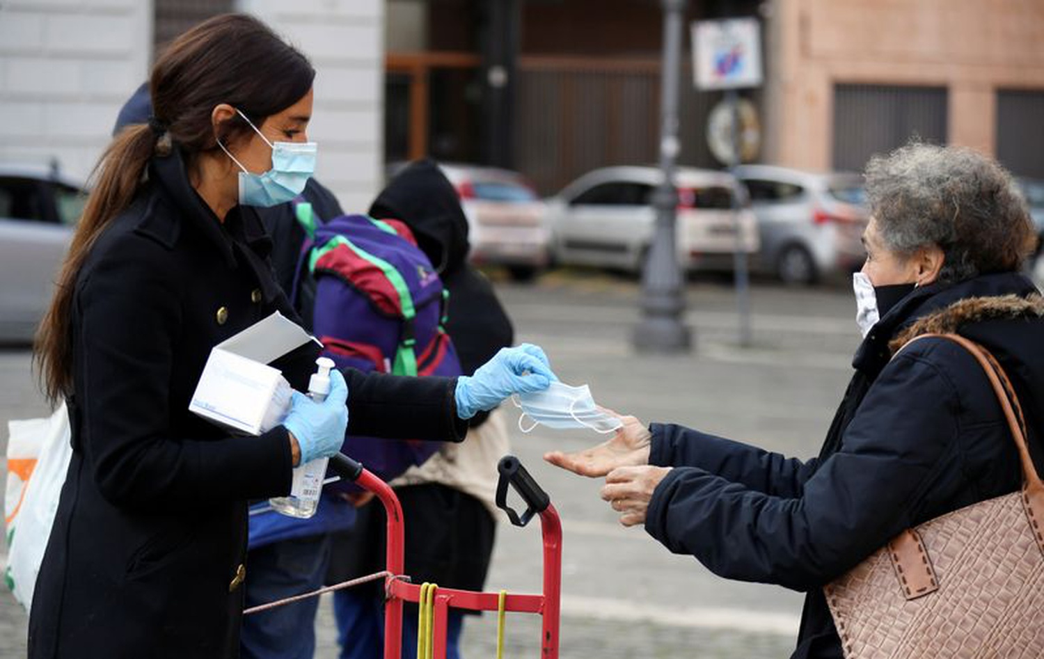 A volunteer hands out a protective face mask to a woman in the Trastevere district, as the spread of coronavirus disease (COVID-19) continues in Rome, Italy, April 02, 2020. (REUTERS)