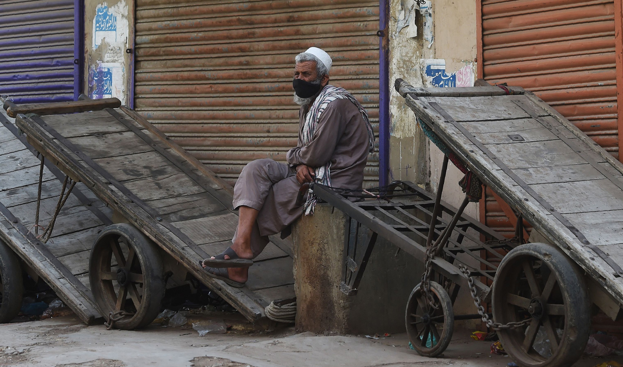 A laborer wearing a facemask sits beside closed shops at a market during a government-imposed nationwide lockdown as a preventive measure against the COVID-19 coronavirus, in Karachi on April 7, 2020. (AFP)