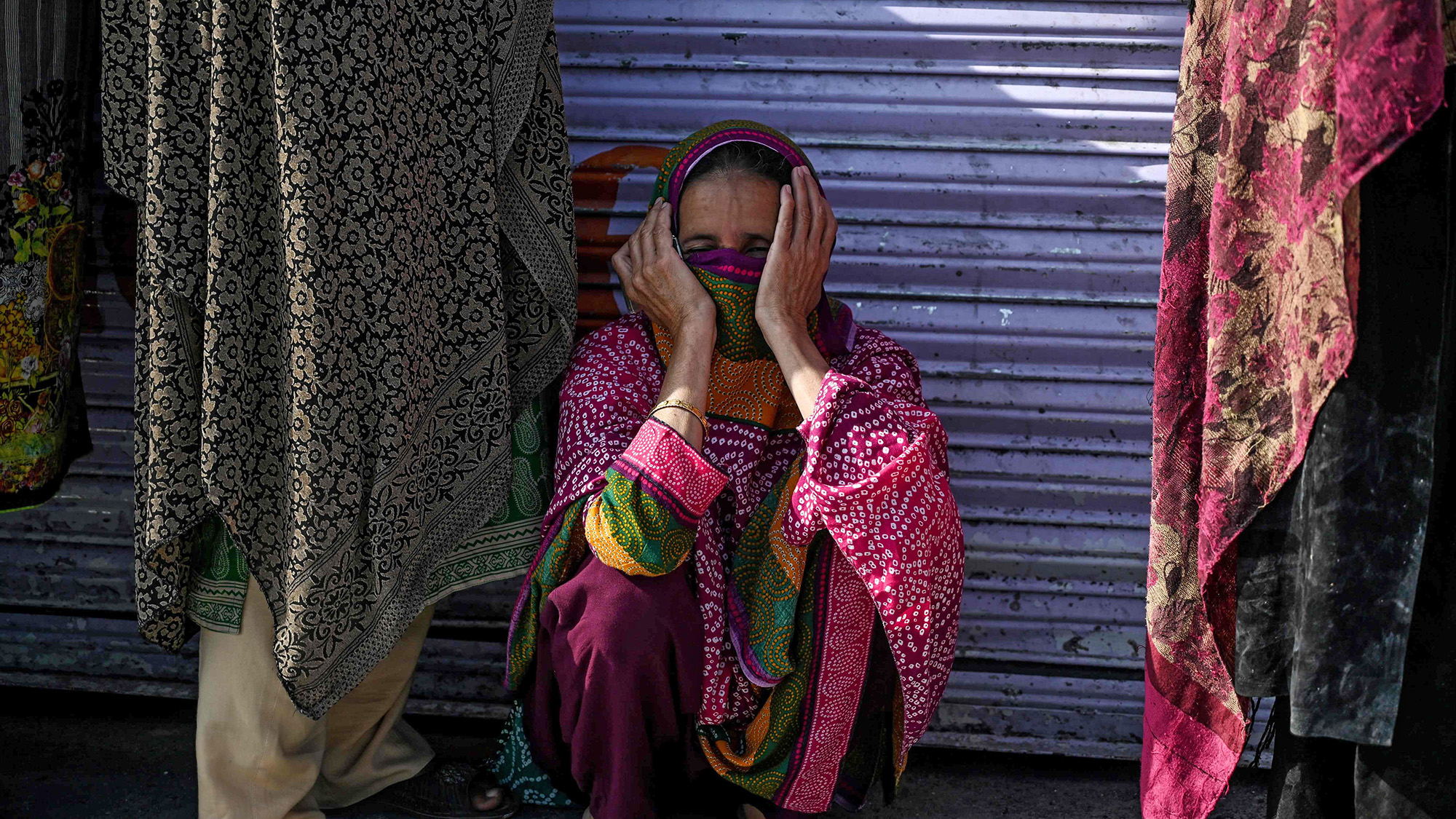 A woman sits as she queues with others to collect cash of financial assistance through a mobile wallet under the governmental Ehsaas Emergency Cash Programme for families in need during a government-imposed nationwide lockdown as a preventive measure against the COVID-19 coronavirus in Islamabad on April 9, 2020. (AFP)