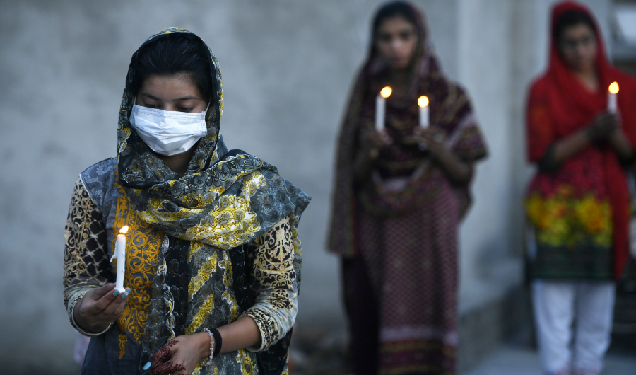 Christians hold candles as they offer prayers during an Easter service in the rooftop of their house during a government-imposed nationwide lockdown as a preventive measure against the COVID-19 coronavirus, in Islamabad on April 12, 2020. (AFP)