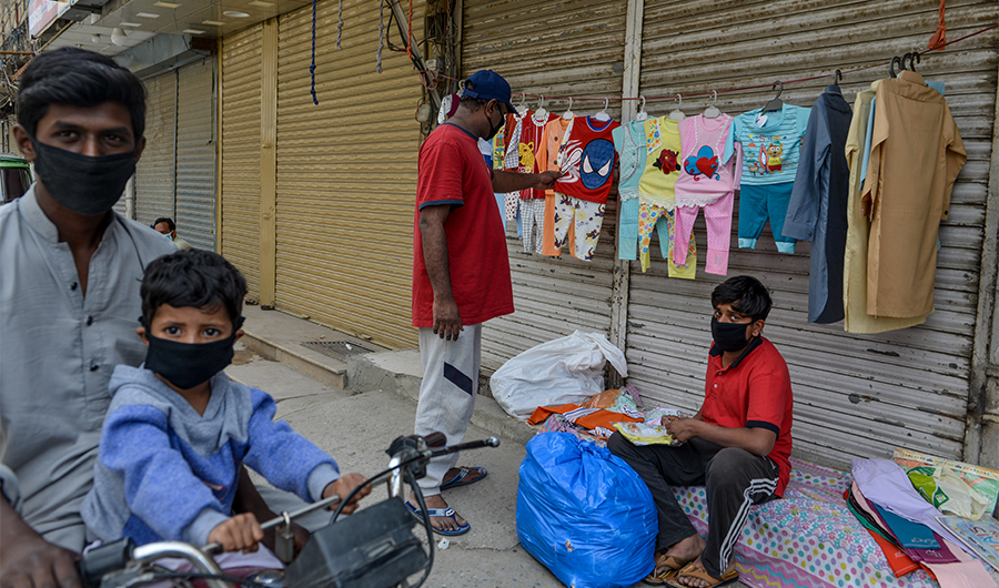 People wearing facemasks buy kids clothes from a roadside vendor during a government-imposed nationwide lockdown as a preventive measure against the COVID-19 coronavirus, in Rawalpindi on April 11, 2020. (AFP)
