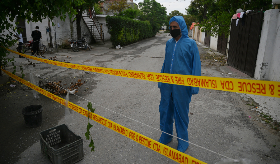 A policeman wearing a hazmat suit stands guard in a cordoned-off area after residents tested positive for coronavirus during a government-imposed lockdown to prevent the spread of COVID-19 in Islamabad on April 19, 2020. (AFP)