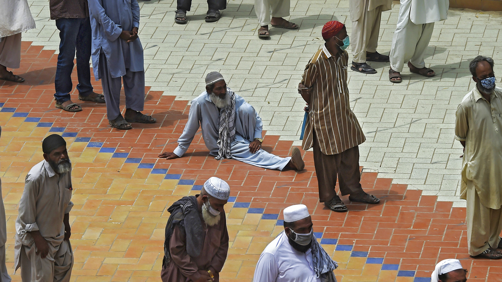 People wait in lines to collect cash from a bank under the governmental Ehsaas Emergency Cash Programme for families in need during a nationwide lockdown as a preventive measure against the spread of the COVID-19 coronavirus in Karachi on April 16, 2020. (AFP)