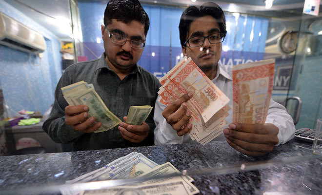 In this file photo, Money dealers count Pakistani rupees, right, and US dollars at a currency exchange in Islamabad on March 12, 2014. (AFP)
