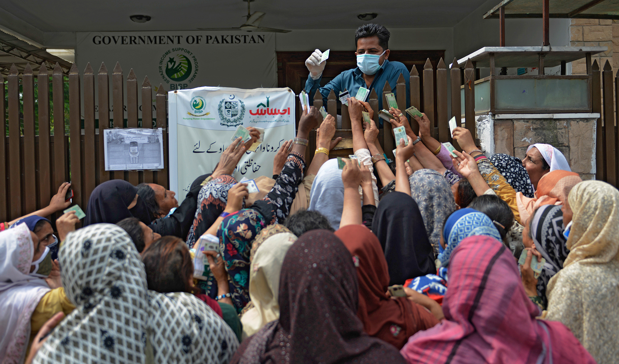 Women gather to collect cash through a mobile wallet under the governmental Ehsaas Emergency Cash Programme for families in need during a government-imposed nationwide lockdown as a preventive measure against the COVID-19 coronavirus, in Rawalpindi on April 14, 2020. (AFP)