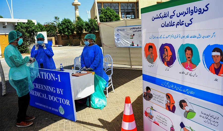 Medical staff members wearing protective gear gather around a desk at a drive-through screening and testing facility point during a government-imposed nationwide lockdown as a preventive measure against the COVID-19 coronavirus, at the port city of Karachi on April 4, 2020. (AFP)
