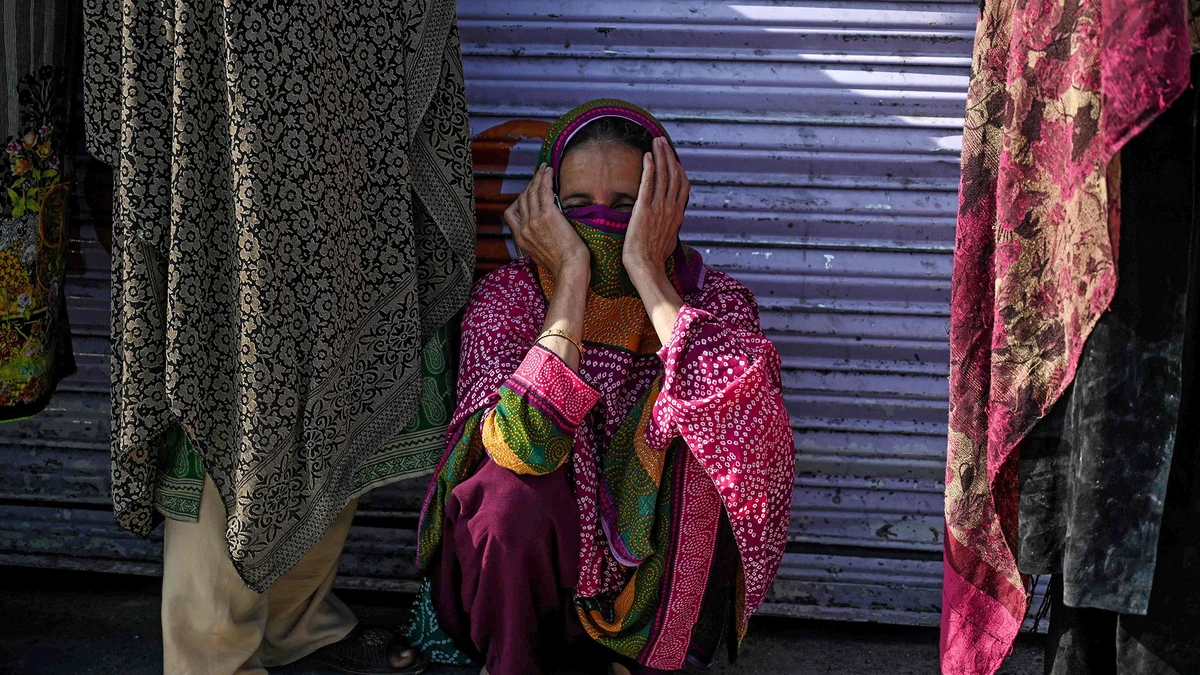 A woman sits as she queues with others to collect cash of financial assistance through a mobile wallet under the governmental Ehsaas Emergency Cash Programme for families in need during a government-imposed nationwide lockdown as a preventive measure against the COVID-19 coronavirus in Islamabad on April 9, 2020. (AFP)