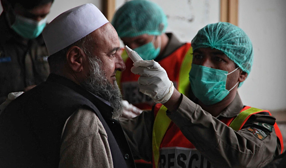 A health official of an emergency rescue service checks the body temperature of a government employee in Peshawar, Pakistan, March 12, 2020. A health official of an emergency rescue service checks the body temperature of a government employee in Peshawar, Pakistan, March 12, 2020. (AP)