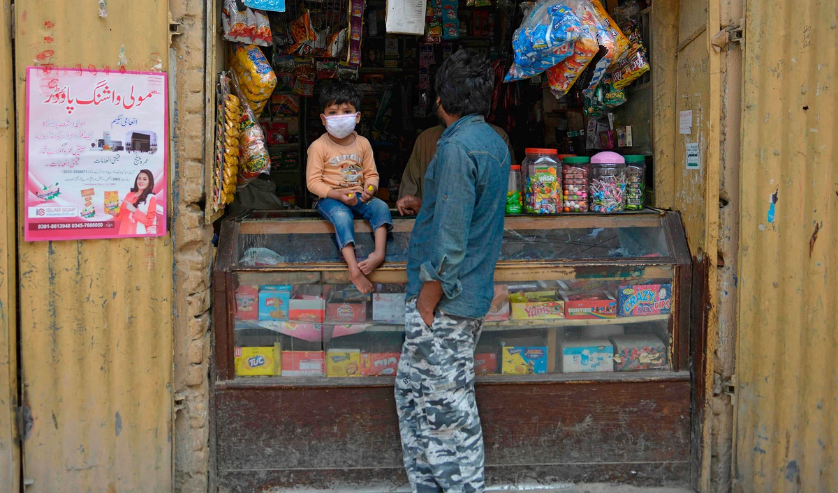 A man stands along with his son which wears a facemask at a shop during a government-imposed nationwide lockdown as a preventive measure against the COVID-19 coronavirus, in Rawalpindi on April 13, 2020. (AFP)