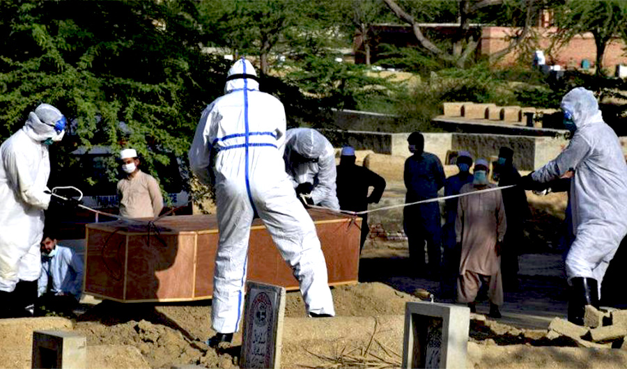 Municipality workers wearing protective suits bury a coronavirus victim at a cemetery on the outskirts of Bahawalpur, in central Pakistan, Sunday, April 5, 2020. (AP)